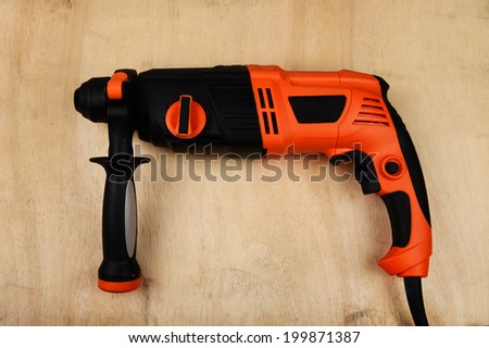 Rotary hammer on wood background