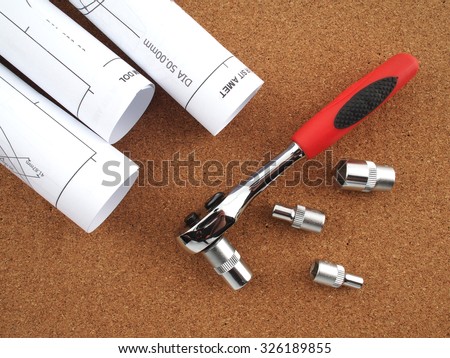 socket wrench and plans on wood background
