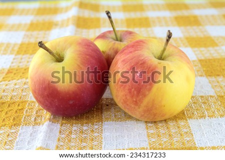 Five red apples on a yellow and white towel with background.