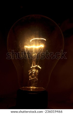 Bright light bulb turned on over black background.