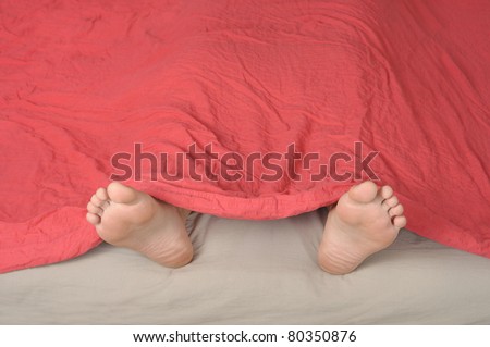 feet detail of sleeping person lying in bed