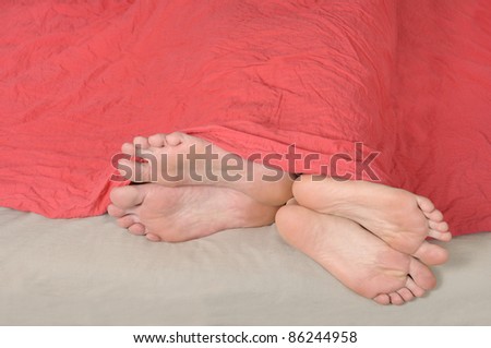 feet detail of couple sleeping in bed