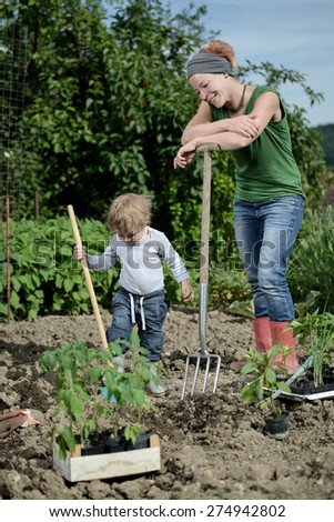 Mom and son planting vegetables in the garden yard