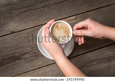 Womans hands holding hot cup of coffee. View from top on a warm coffee cup.