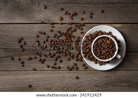 Coffee cup with roasted coffee beans on wooden table. View from top