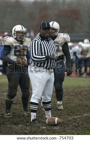 Football referee with high school football players. Editorial use only.