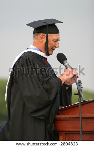 School administrator speaking at a high school graduation. Editorial use.