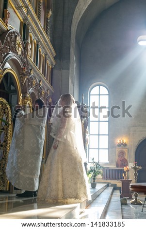 MOSCOW - MARCH 10: bride and groom stand opposite the iconostasis in the rays of light during orthodox wedding ceremony on March 10, 2013 in Moscow