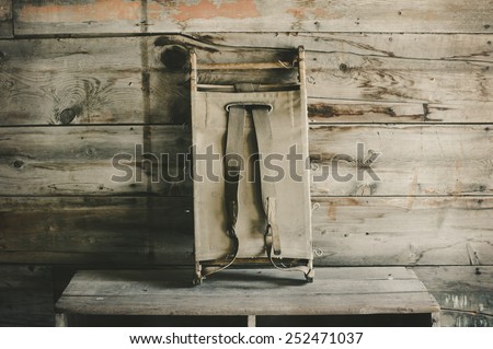 Vintage child size canvas stretcher resting against wooden wall.
