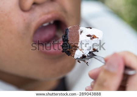 male eating a bite of decadent chocolate peanut butter cake