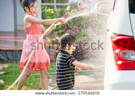 Asian children washing car in the garden