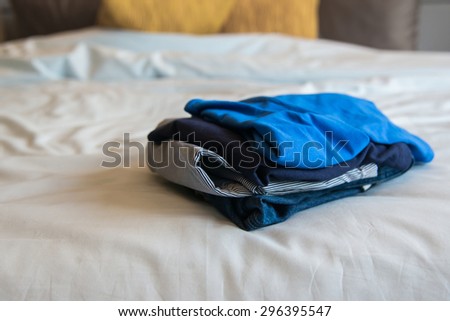 Close up pile of clothing on white bed
