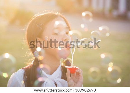 Cute asian girl is blowing a soap bubbles,vintage filter