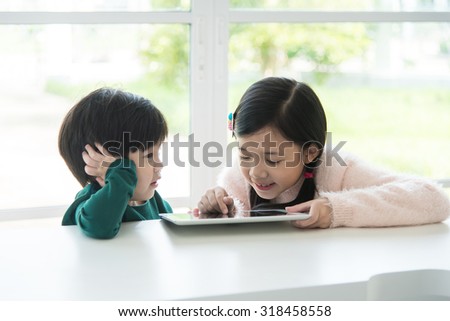 Cute asian children using tablet on white table