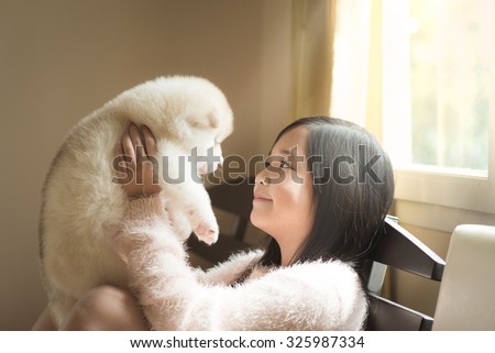 Little asian playing with a siberian husky puppy on the bed,vintage filter