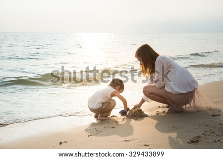 mother and son playing on the beach,vintage filter