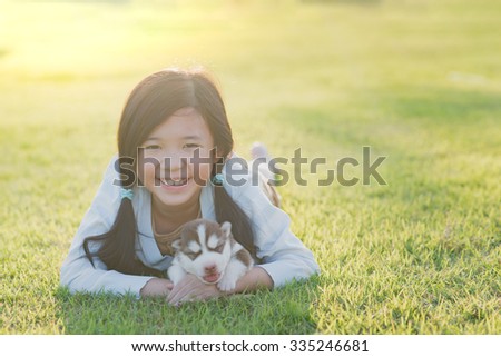 Cute asian girl lying with her puppy on green grass