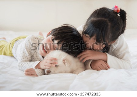 Little asian children and puppy having fun lying in bed