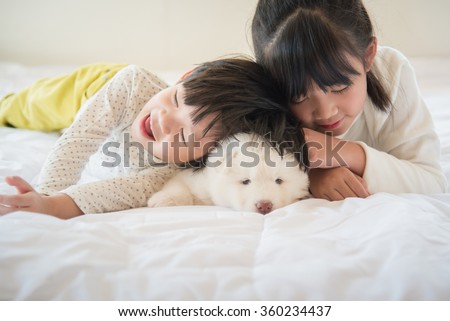 White siberian husky lying with asian children on white bed