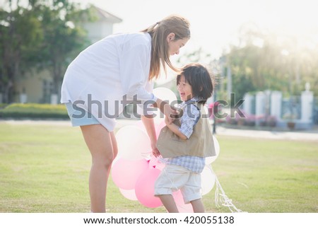 Asian mother and son holding hand together and walking in the park under sunlight