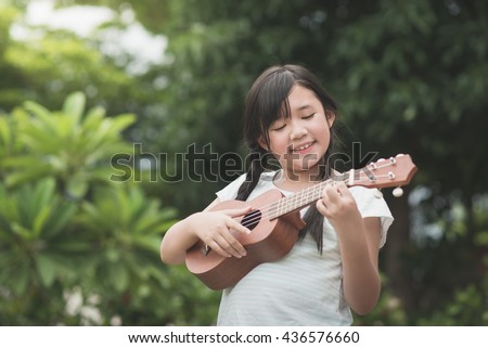Beautiful asian girl playing ukulele, Outdoor portrait