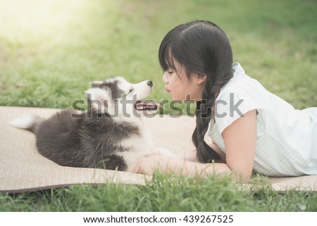 Beautiful asian girl playing with siberian husky puppy in the park,vintage filter
