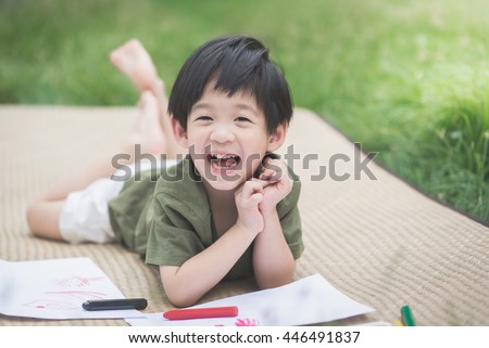 Cute Asian child drawing picture with crayon