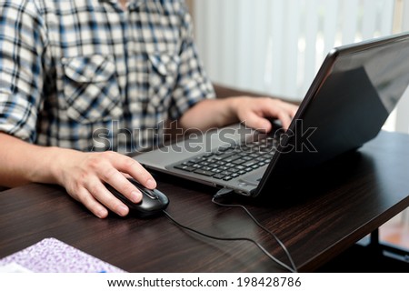 Hands of caucasian man holding a mouse and printing on a keyboard