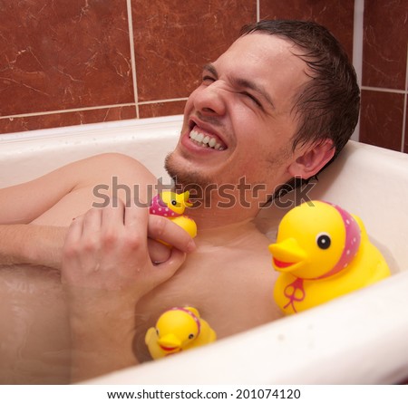 Adult happy man is taking bath with toy duck