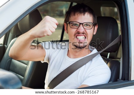 Male caucasian angry driver is showing his fist and mad face