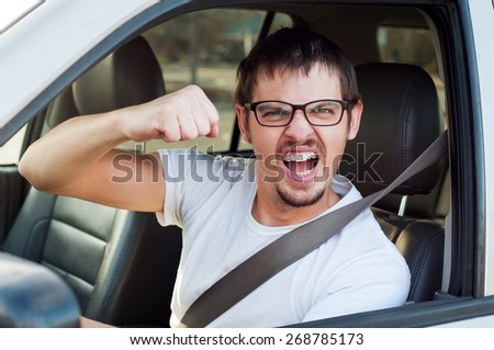 Male white angry driver is showing his fist and mad face