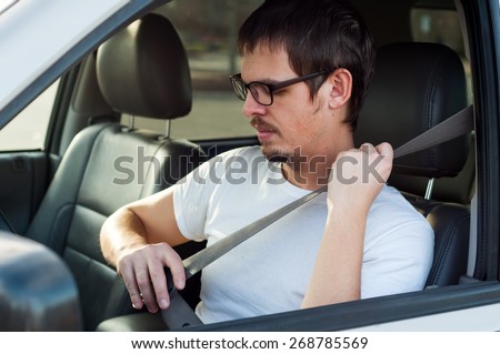 Male european driver is using seat belt in a car
