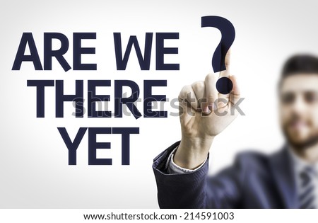 Business man pointing to transparent board with text: Are We There Yet?