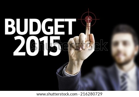 Business man pointing to black board with text: Budget 2015