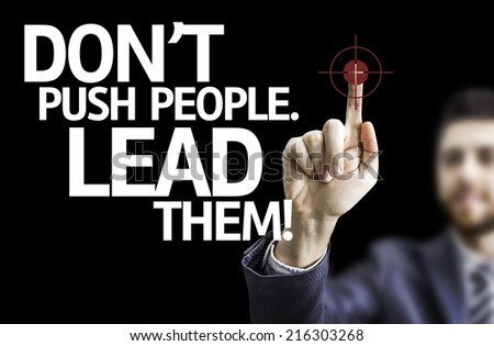 Business man pointing to black board with text: Don\'t Push People, Lead Them!