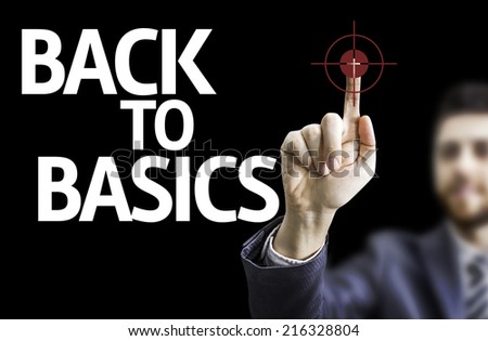 Business man pointing to black board with text: Back to Basics