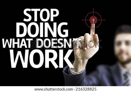 Business man pointing to black board with text: Stop Doing What Doesn\'t Work