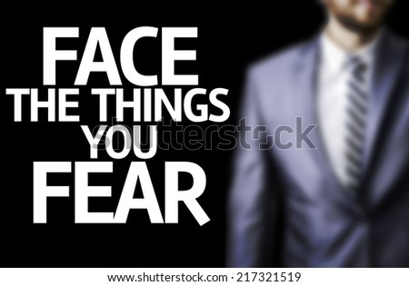 Face the Things you Fear written on a board with a business man on background