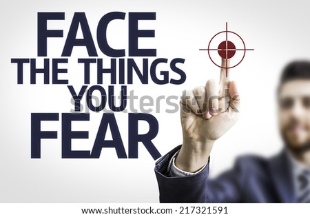 Business man pointing to transparent board with text: Face the Things you Fear