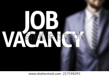 Job Vacancy written on a board with a business man on background
