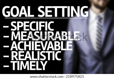 Description of Goal Setting written on a board with a business man on background