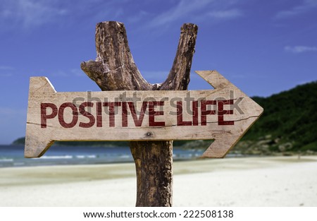 Positive Life wooden sign with a beach on background