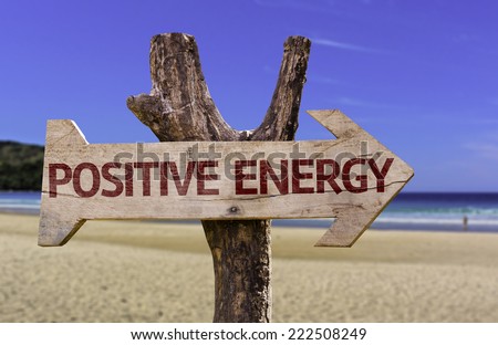 Positive Energy wooden sign with a beach on background