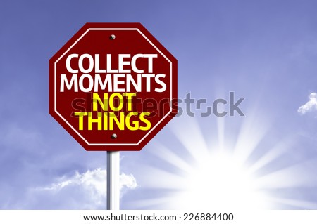 Collect Moments Not Things written on red road sign with a sky on background