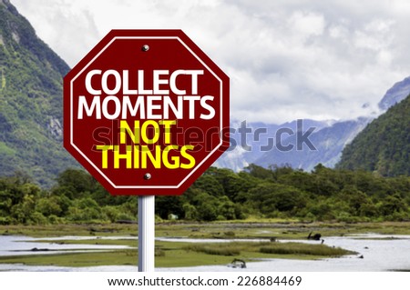 Collect Moments Not Things written on red road sign with landscape background