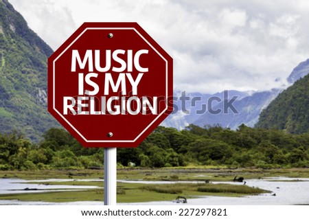 Music Is My Religion written on red road sign with landscape background