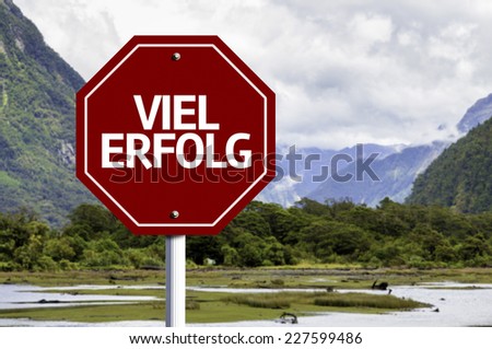 Much Success (In German) written on red road sign with landscape background