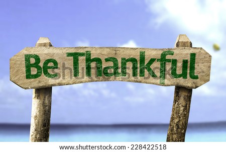 Be Thankful sign with a beach on background