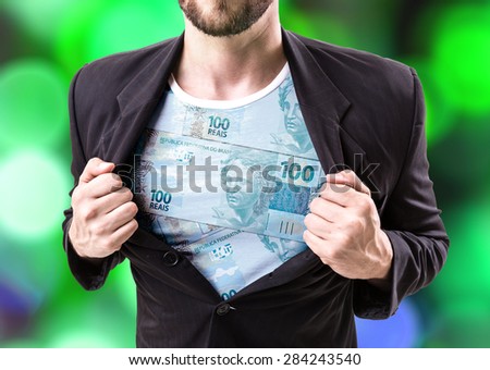 Businessman stretching suit with Brazilian money on bokeh background