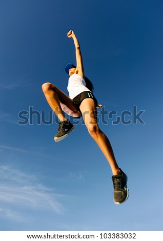 Athlete celebrating jumping and leaping against a blue sky. healthy wellness fitness woman in air